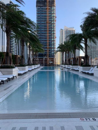 Poolside view looking towards a tall building under construction with other skyscrapers in the background.