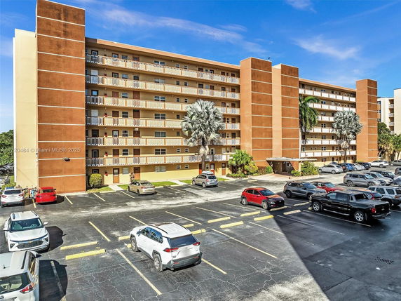 Front view of a multi-story residential building with a parking area in front.