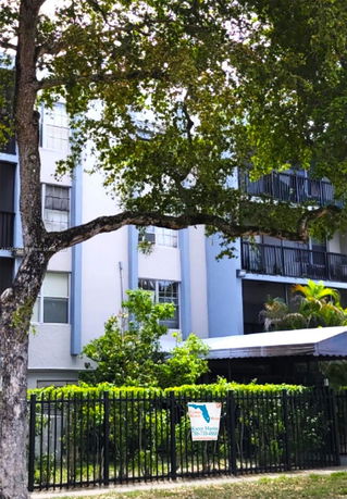 Front view of a multi-story building with balconies and a metal fence.