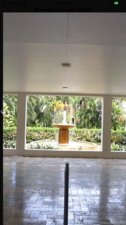 View from a covered area looking out towards a garden with a central water fountain.