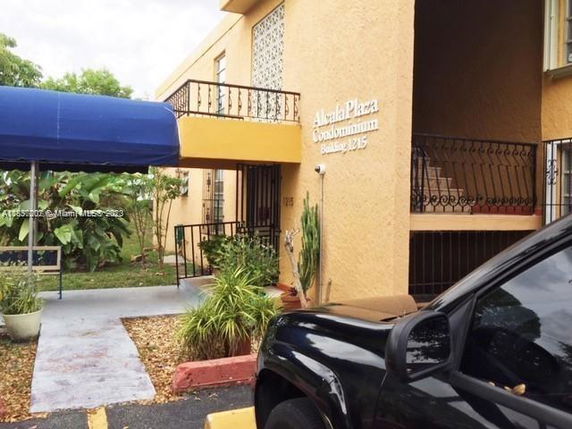 Front view of a condominium building with an entrance canopy and stairs.