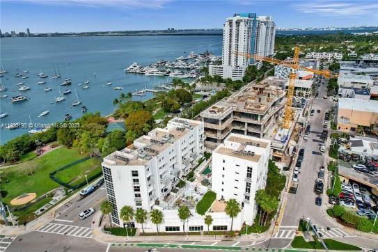 Aerial view of a coastal area with multiple buildings and a marina with boats docked.