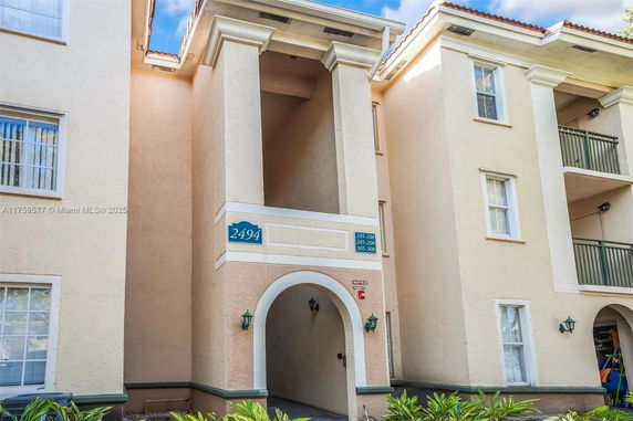 Front view of a multi-story building entrance with columns and balconies.