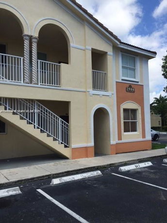 Front view of a two-story residential building with a staircase and arches.