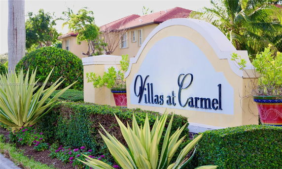 Entrance sign for Villas at Carmel with a building in the background.