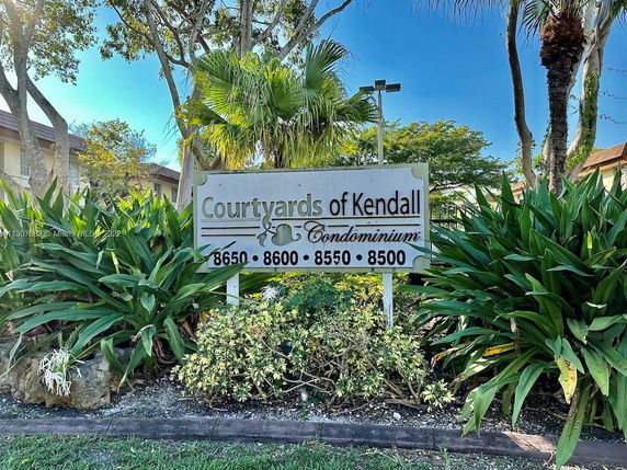 Front view of Courtyards of Kendall condominium with a visible sign.