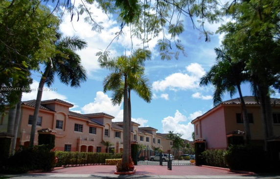 Front view of a residential building complex with multiple townhouses and gated entry.