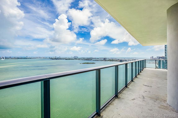 Panoramic view from a high-rise building's balcony overlooking a large body of water and city skyline.