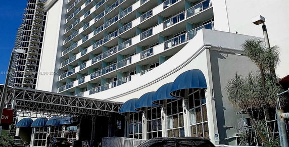 Front view of a high-rise building with multiple balconies and blue awnings.