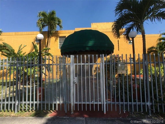Front view of a building with a gated entrance and a green canopy.