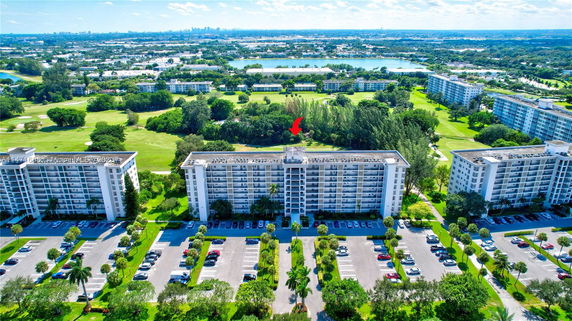 Aerial view of apartment buildings surrounded by greenery and other buildings in the background.