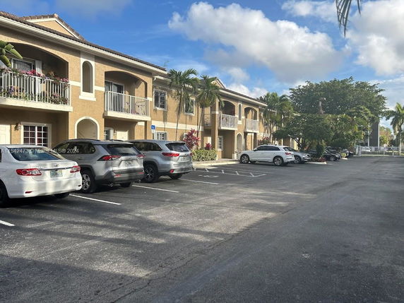 Outdoor parking area in front of a two-story building with balconies.