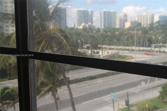 View from a window showing a road and distant high-rise buildings.
