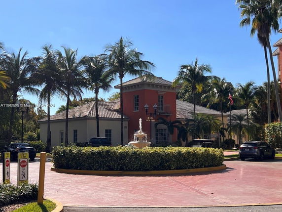 Front view of a building with palm trees and a central fountain.
