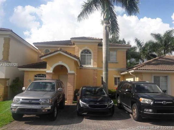 Front view of a two-story house with stucco exterior and arched entrance.