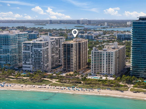 Aerial view of beachfront high-rise buildings with coastline and cityscape in the background.
