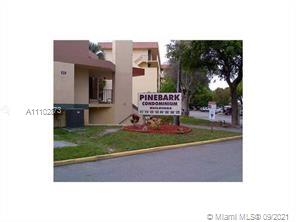 Front view of a condominium building with a sign labeled 'Pinebark Condominiums'.