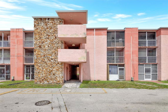 Front view of a multi-story building with stone and pink facade.