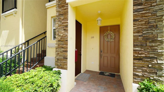 Front view of a house entrance with a brown door and stone accent walls.