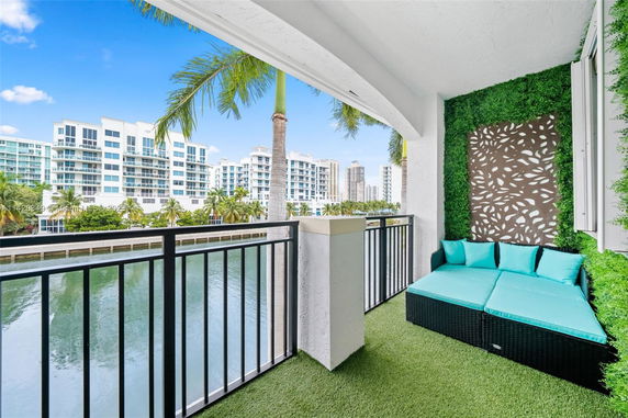 Balcony view overlooking water with modern high-rise buildings in the background.