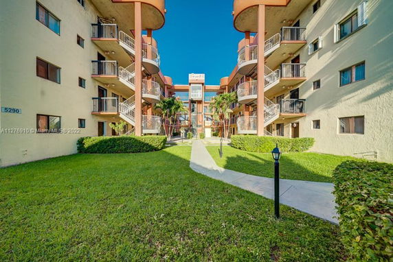 Front view of a residential building with balconies and a walkway leading to the entrance.