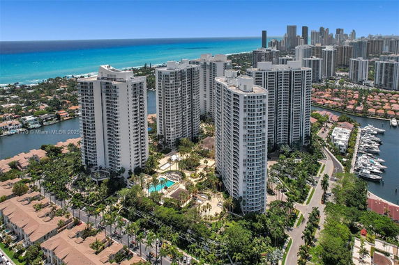 Panoramic view of tall residential buildings near the coast with cityscape and ocean in the background.
