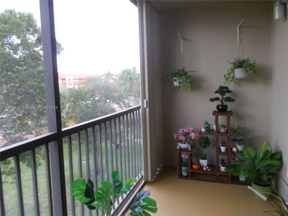 Balcony view with potted plants and surrounding trees visible.