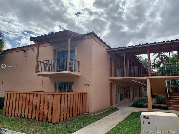 Front view of a two-story residential building with balconies and a tiled roof.