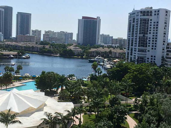 Panoramic view of tall buildings and water body with surrounding greenery.