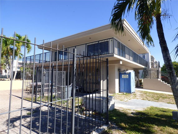 Front view of a two-story building with balconies and a gated entrance.