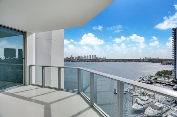 Balcony overlooking a body of water with distant city skyline and marina view.