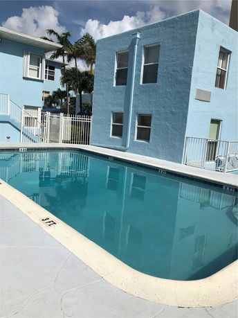 Outdoor swimming pool beside a blue two-story building.