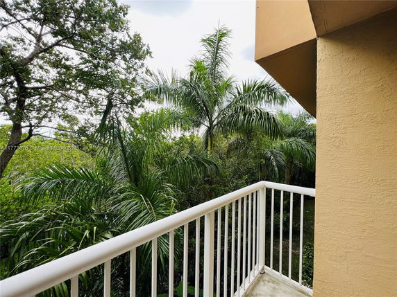 View from a balcony overlooking lush green trees.