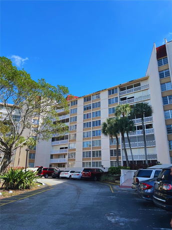 Front view of a multi-story residential building with balconies and parking area.
