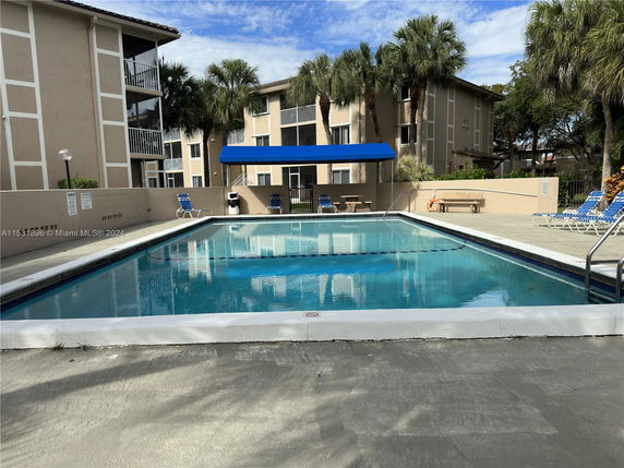 Outdoor swimming pool in front of a multi-story residential building.