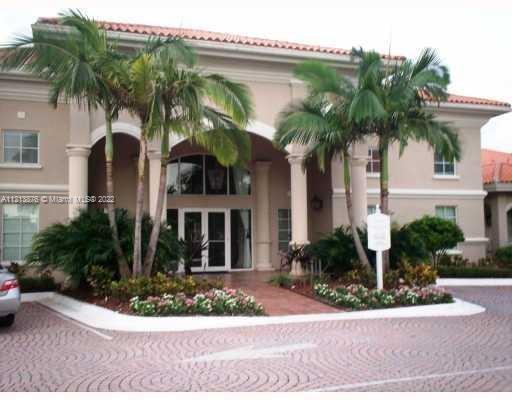 Front view of a two-story house with a covered entrance and palm trees in front.