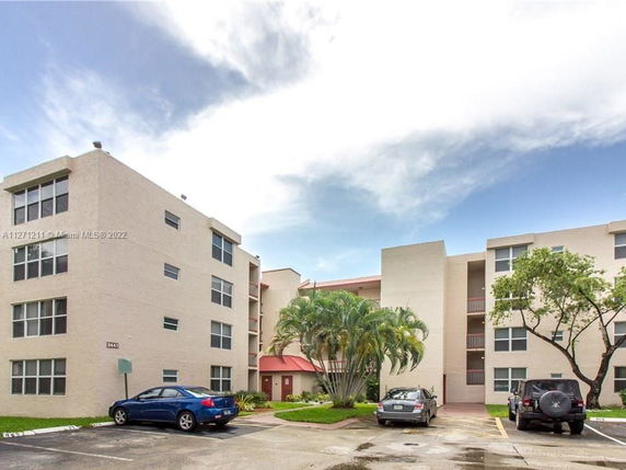 Front view of a multi-story apartment building with parking area.