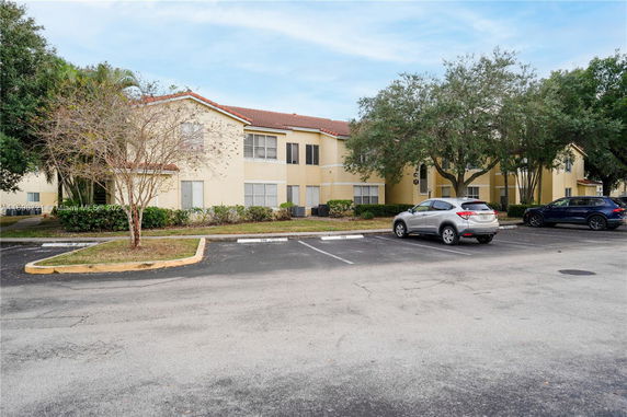 Front view of a two-story residential building with a parking area.