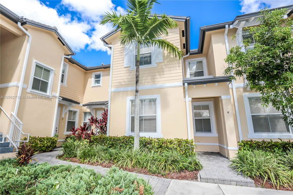 Front view of a two-story townhouse with a light tan exterior and white trim.
