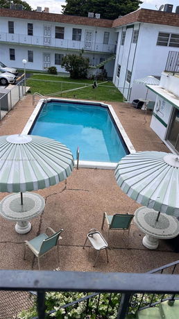Outdoor swimming pool area with umbrellas and seating.