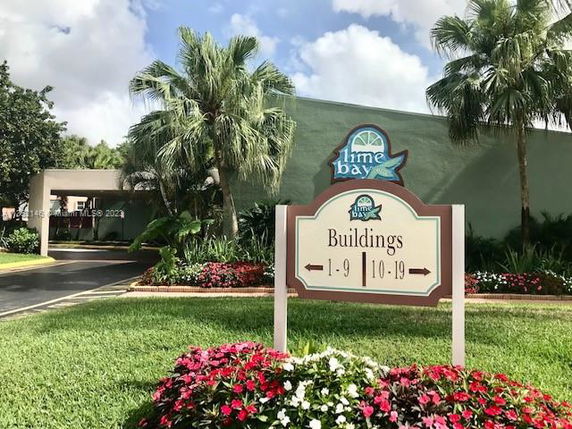 Front view of a building with a sign directing to various building numbers.