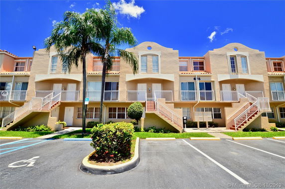 Front view of a multi-story residential building with balconies and exterior staircases.