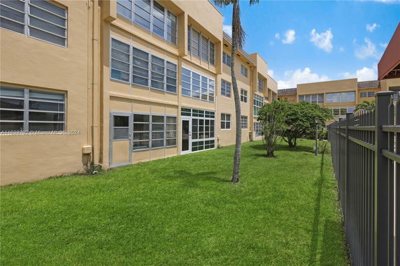 Side view of a multi-story building with large windows and a grassy area.