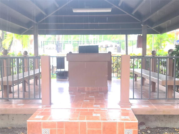 Outdoor pavilion with tiled flooring and benches under a roof.