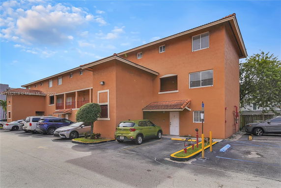 Front view of a multi-story building with parking area in front.