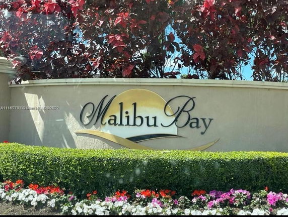 Entrance sign with flowers and greenery for a place named Malibu Bay.