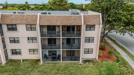 Front view of a multi-story apartment building with balconies and a pitched roof.