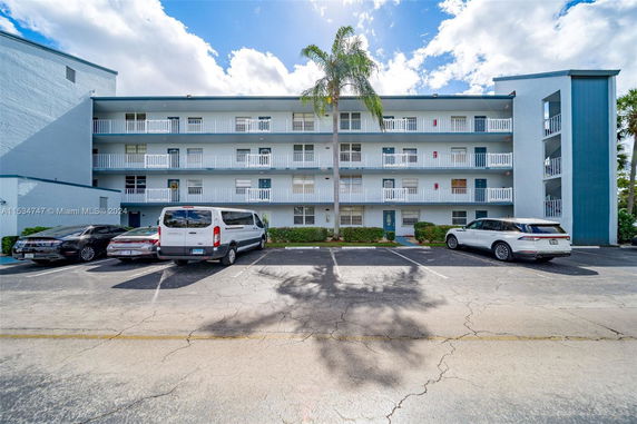 Front view of a multi-story residential building with balconies and parking area.
