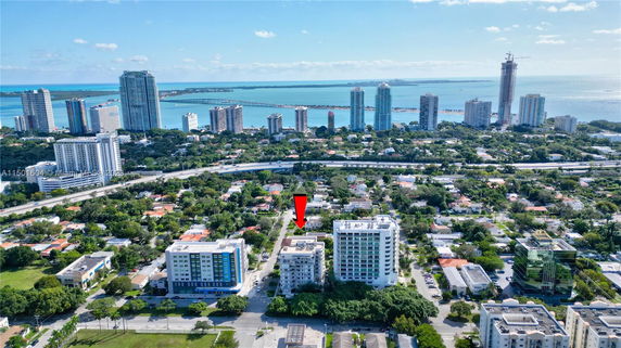Aerial view of a coastal urban area with numerous buildings, roads, and distant water body.