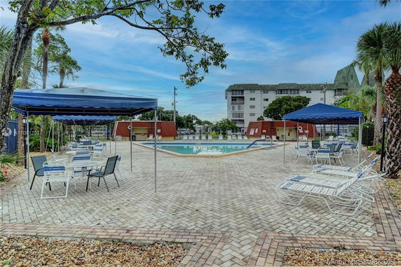 Outdoor swimming pool area with lounge chairs and canopies.